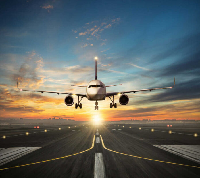 Airplane landing on runway during sunset sky