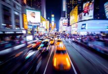 Yellow taxis speed through a neon-lit city street at night