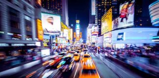 Yellow taxis speed through a neon-lit city street at night