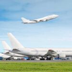 Commercial airplanes at airport with one taking off