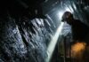 miner with headlamp working in a dark tunnel