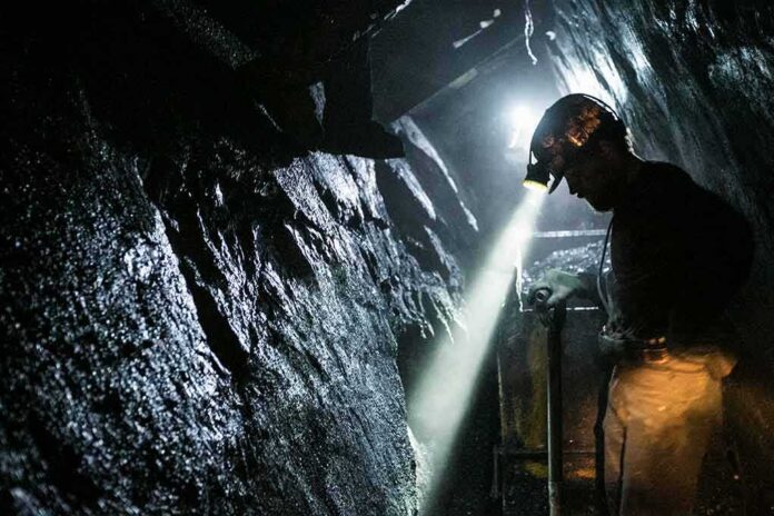 shutterstock_1153891762 miner with headlamp working in a dark tunnel