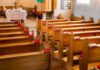 Empty wooden church pews with red hymnals