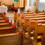 Empty wooden church pews with red hymnals