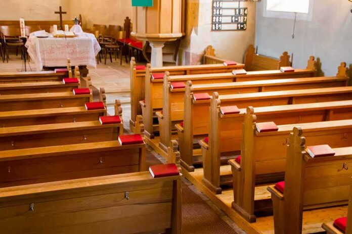 shutterstock_1203956791 Empty wooden church pews with red hymnals