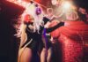 Drag performer singing on stage with dramatic lighting