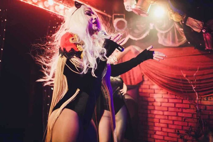 Drag performer singing on stage with dramatic lighting