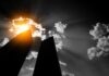 Silhouetted skyscrapers under dramatic sunburst and clouds