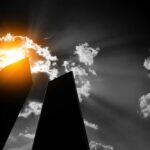 Silhouetted skyscrapers under dramatic sunburst and clouds