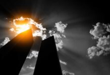 Silhouetted skyscrapers under dramatic sunburst and clouds
