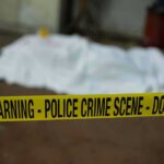 crime scene tape in foreground with covered body in background