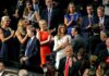 Audience members applauding at a formal indoor event
