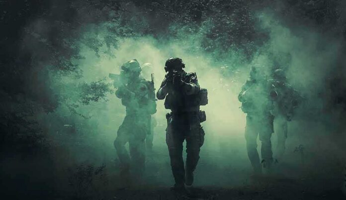 Soldiers move through dense smoke in a forest