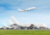 Commercial airplanes at airport with one taking off