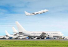 Commercial airplanes at airport with one taking off