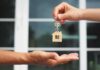 Hands exchanging house-shaped keychain and keys