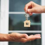 Hands exchanging house-shaped keychain and keys