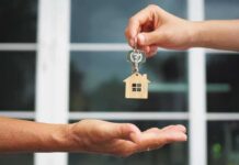 Hands exchanging house-shaped keychain and keys