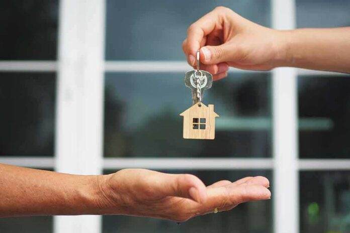 Hands exchanging house-shaped keychain and keys