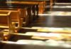 Wooden church pews with stained glass light on the aisle