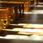 Wooden church pews with stained glass light on the aisle
