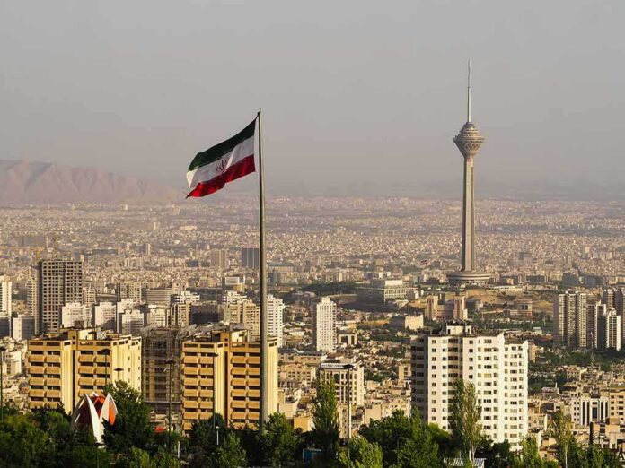 shutterstock_1415273714 Iranian flag over Tehran skyline with Milad Tower
