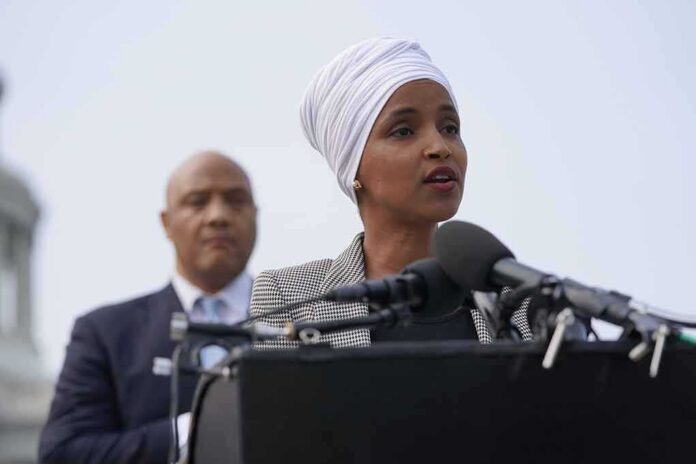 shutterstock_2012384414 Woman in white headwrap speaking at microphones outdoors