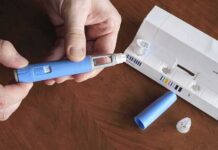 Hands assembling a blue insulin pen with packaging on a table