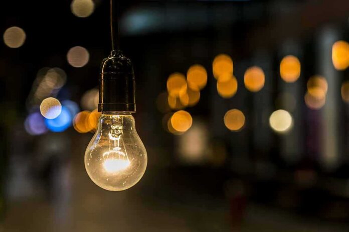 shutterstock_466357037 Light bulb hanging with warm bokeh lights in background