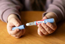 Hands holding an Ozempic injection pen.