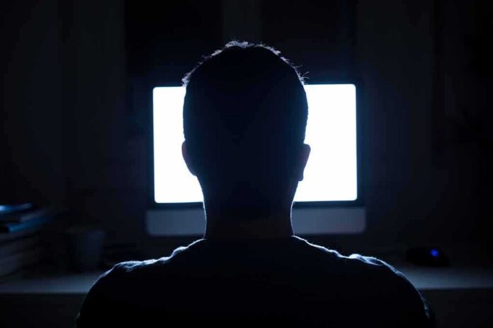 shutterstock_1059872750 person silhouetted in front of a bright computer screen