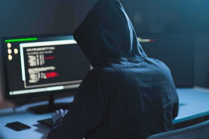 Person in hoodie at dual monitors with code