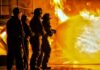 Firefighters battling a large blaze with a hose