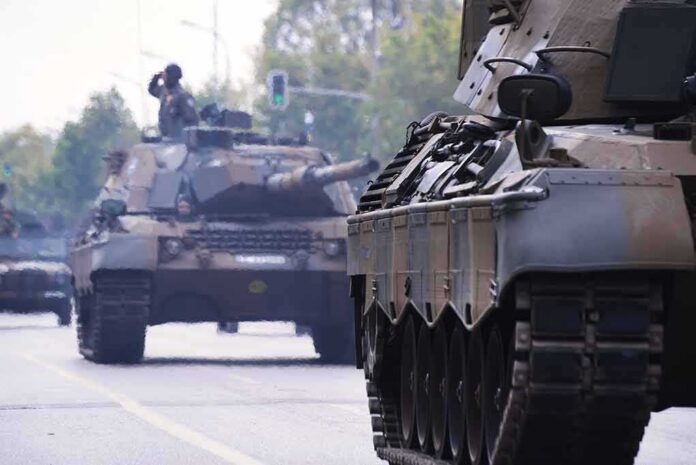 shutterstock_1200057271 Military tanks drive down a city street