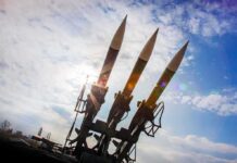 Three surface-to-air missiles on a launcher against a bright sky