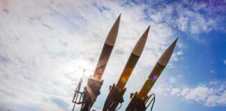 Three surface-to-air missiles on a launcher against a bright sky