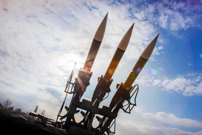 Three surface-to-air missiles on a launcher against a bright sky