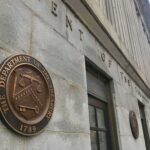 U.S. Treasury building exterior with bronze seal on stone wall