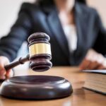 Judge's gavel striking sound block on courtroom desk