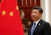 Xi Jinping standing beside a Chinese flag