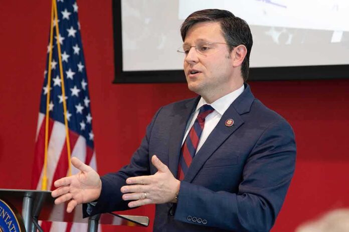 Man in suit speaking at podium with US flag in background