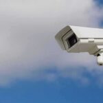security camera mounted on a pole against blue sky