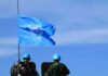 UN flag above peacekeepers in blue helmets