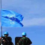 UN flag above peacekeepers in blue helmets