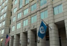 U.S. government building facade with American and blue departmental flags