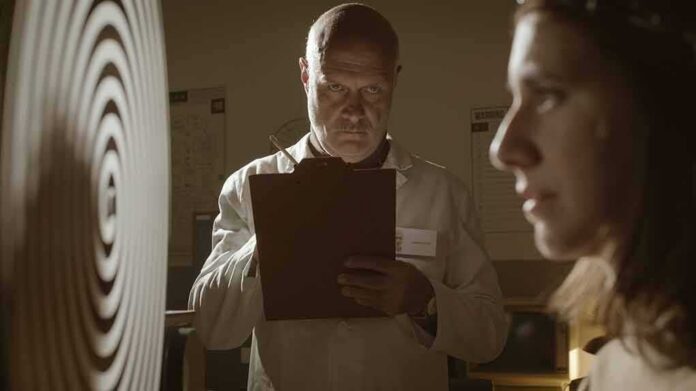 Scientist with clipboard observes woman beside spiral target