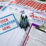 Voter registration table with forms, pens, and informational materials