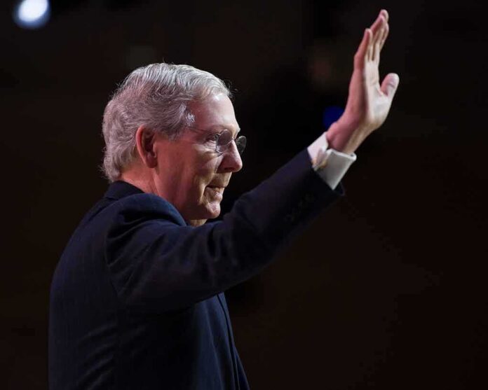 older man in suit raising his hand