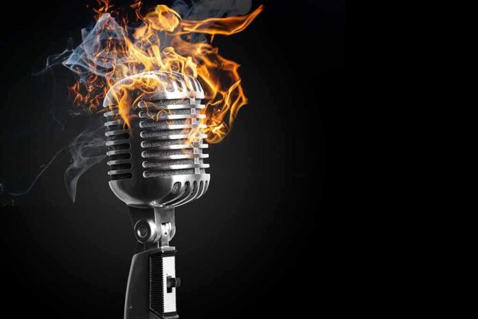 Vintage microphone on fire against a dark background