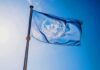United Nations flag waving on a pole against clear blue sky